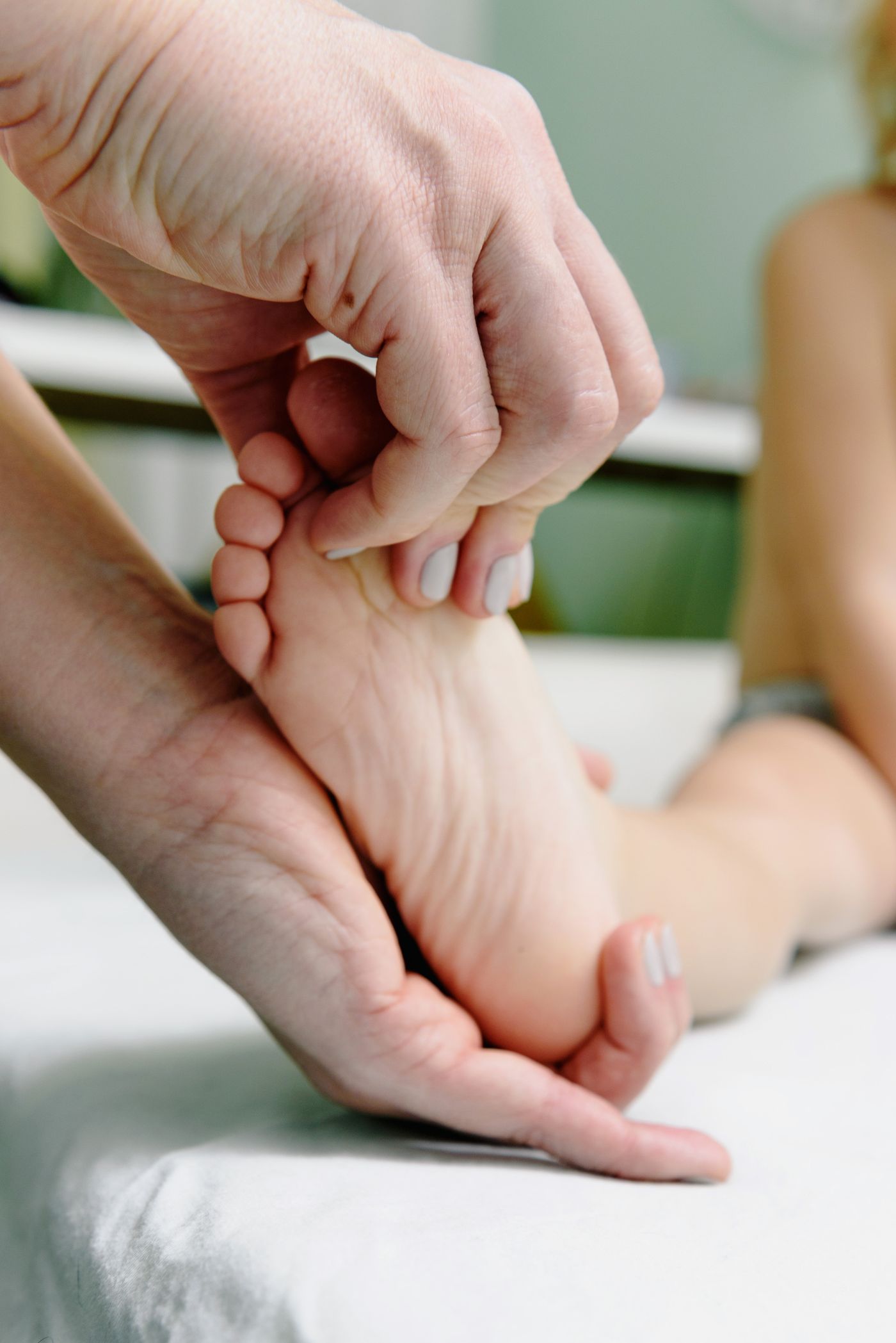 Mains massant délicatement un pied lors d'un soin